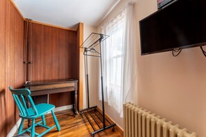 A compact room with a wooden desk, a teal chair, a radiator, and a television mounted on the wall. - Full Lovely Home Walking Distance to Town & Harbor (Mount Desert)