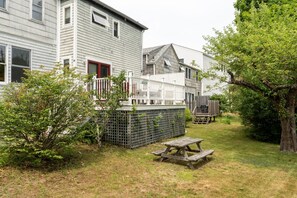 A residential area with a wooden deck, a picnic table, and a fenced yard. - Full Lovely Home Walking Distance to Town & Harbor (Mount Desert)