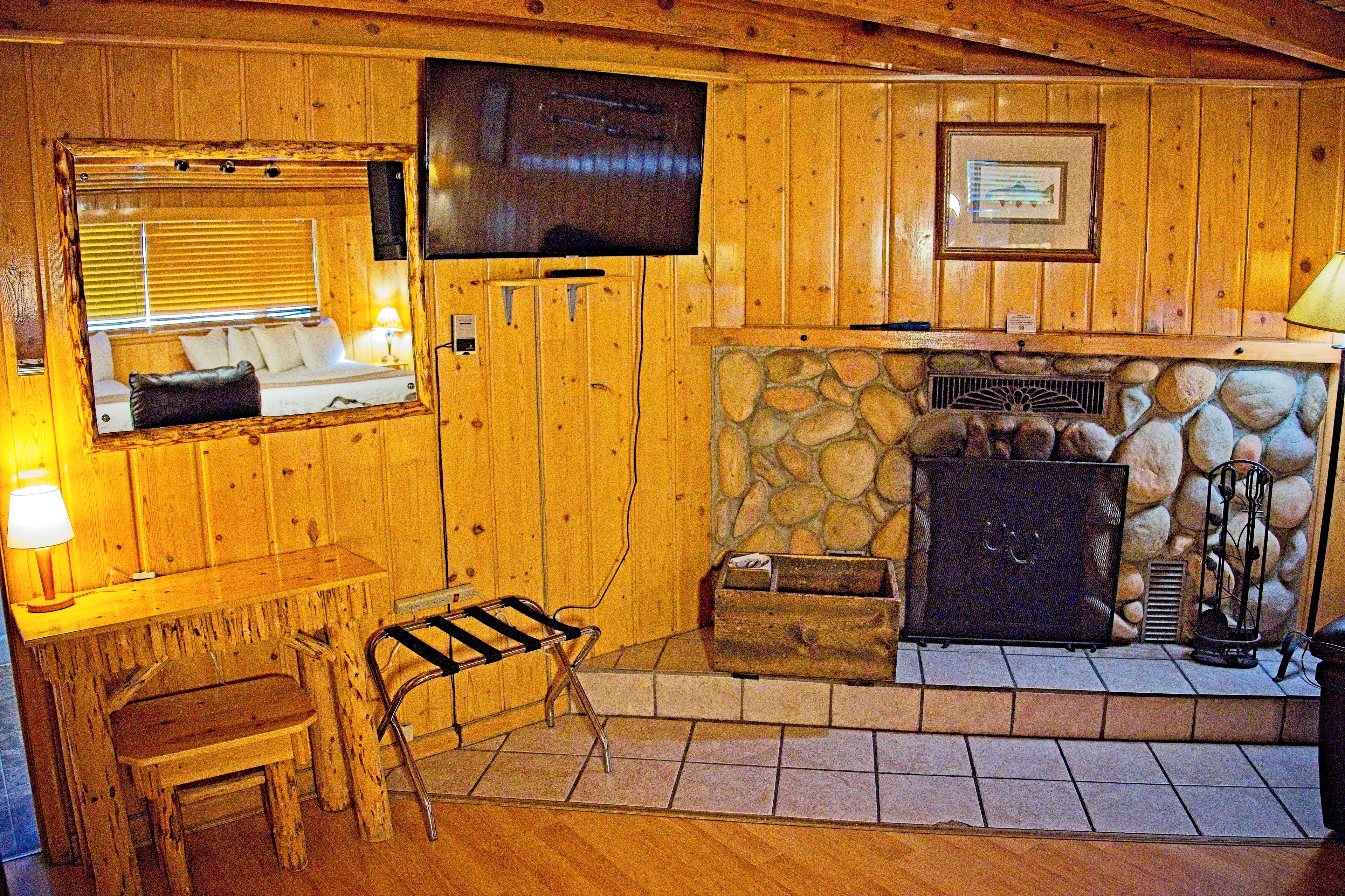 A wooden interior with a fireplace, a television mounted on the wall, and a window with blinds.