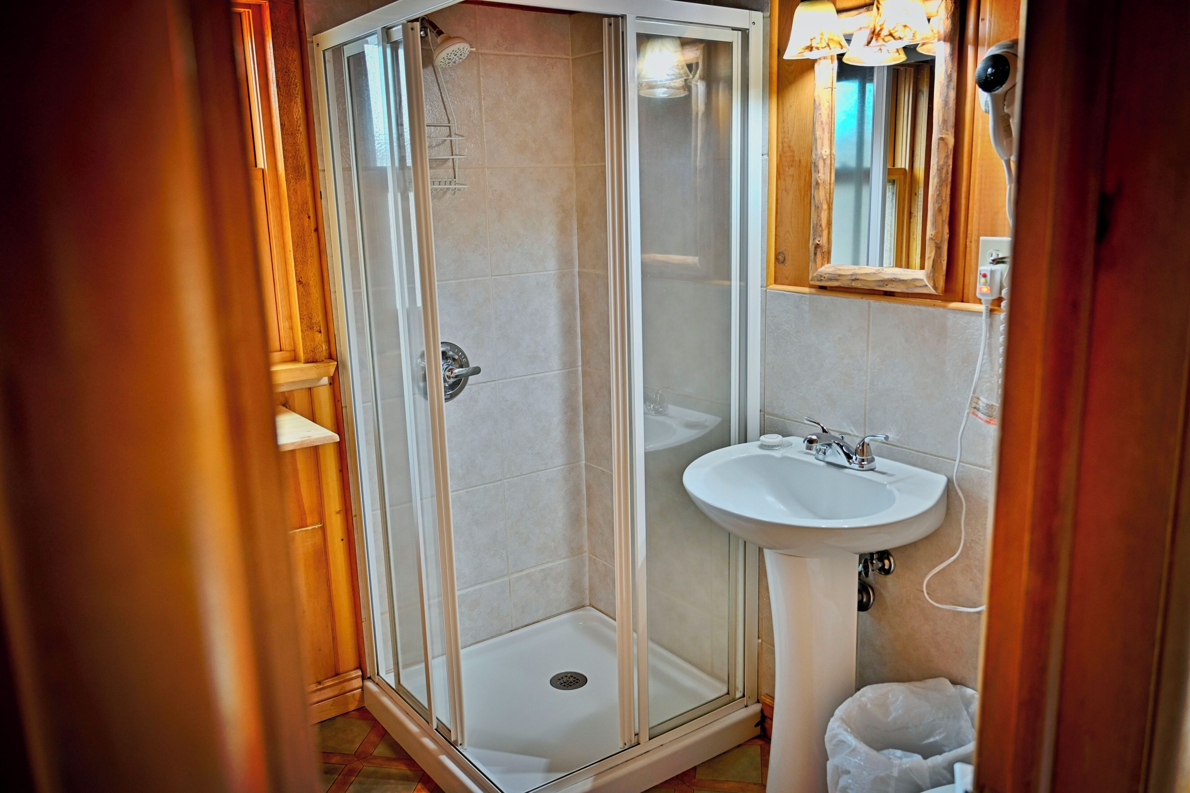 Een badkamer met een douche met glazen wanden, een wastafel en een spiegel.