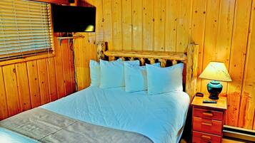 A wooden room with a bed, a nightstand, and a television mounted on the wall.