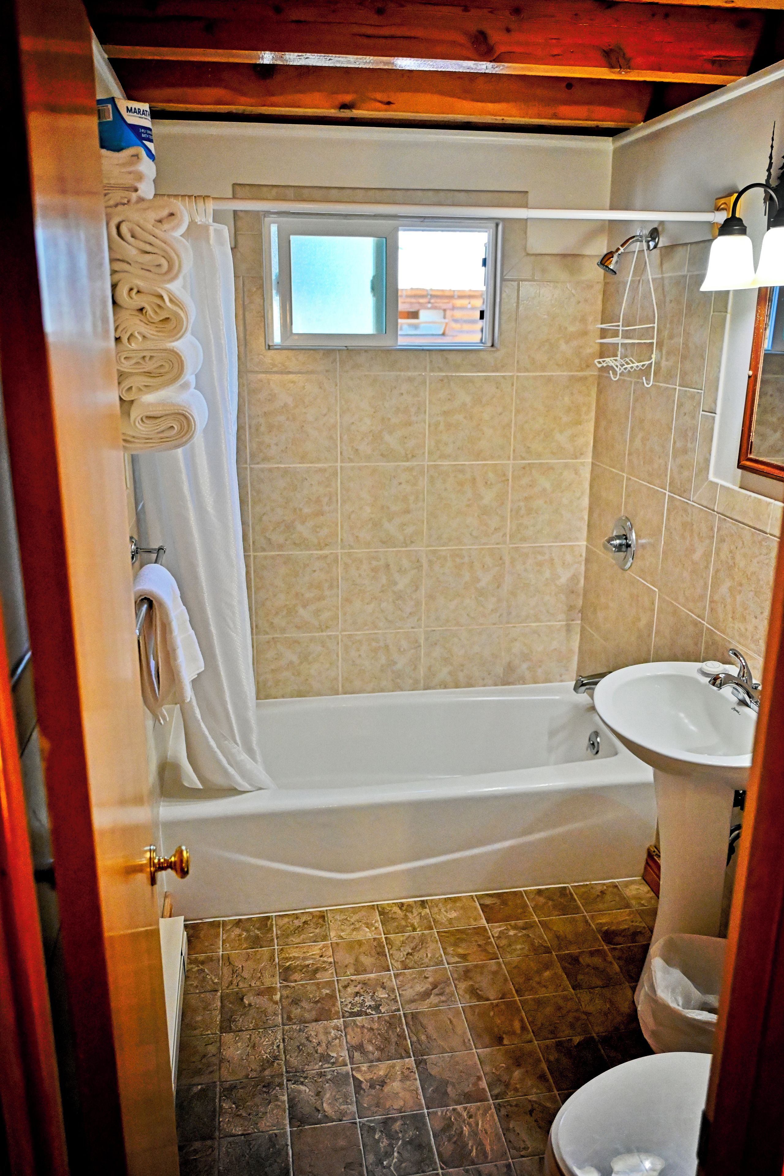 Une salle de bain avec une baignoire, une douche, un lavabo et une fenêtre.