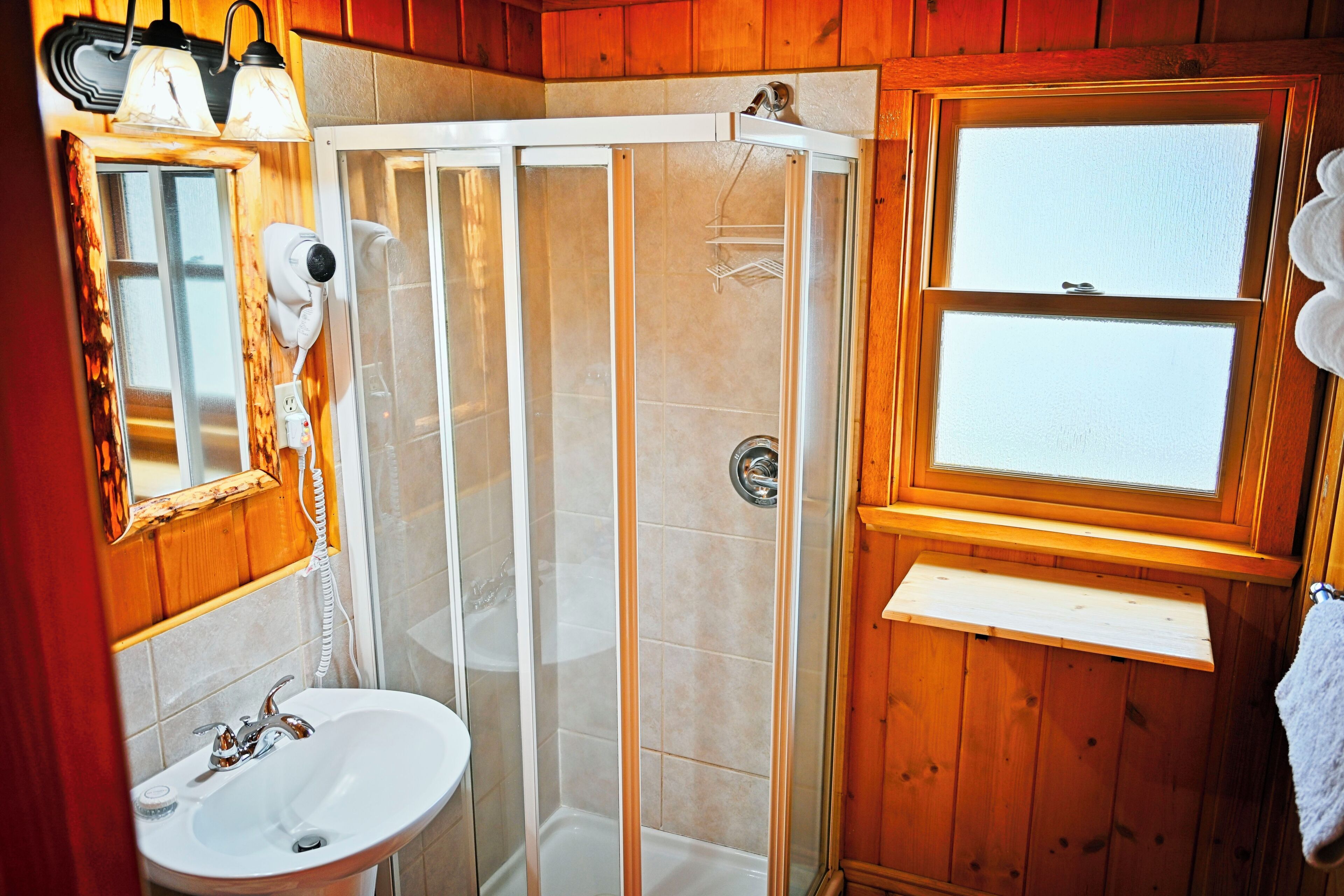 Un baño con ducha, lavabo, espejo y ventana.