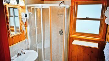 Un baño con ducha, lavabo, espejo y ventana.
