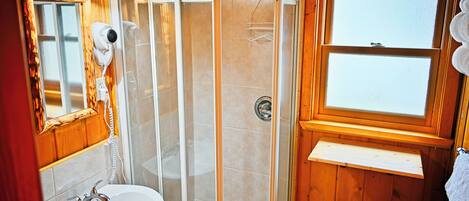 A bathroom with a shower, a sink, a mirror, and a window.