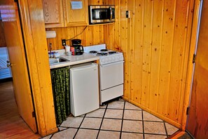Une cuisine compacte équipée d’une cuisinière, d’un four à micro-ondes et d’un petit réfrigérateur.