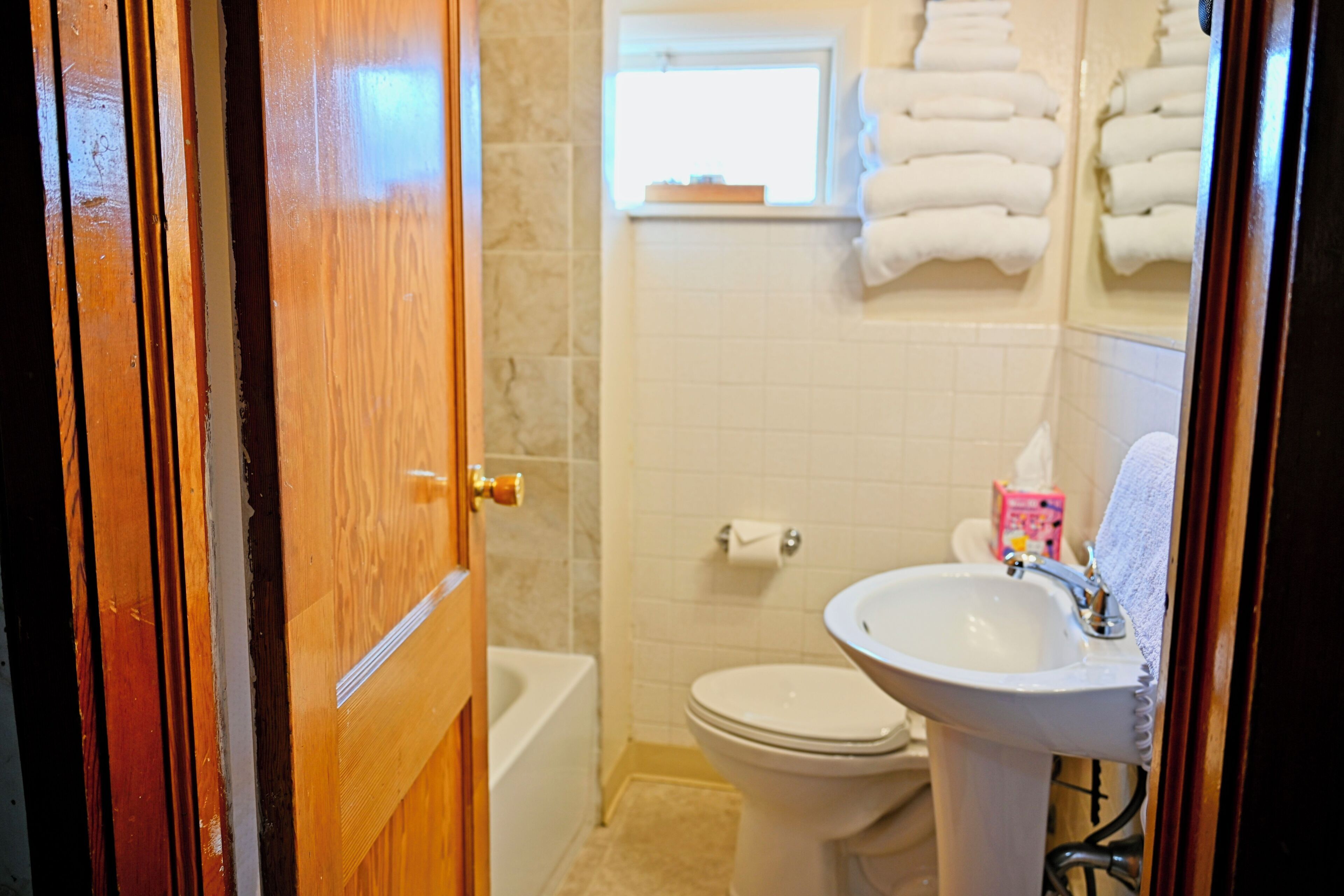 Un baño con inodoro, lavamanos y perchero para toallas.