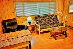 A cozy room with a leather chair, a patterned sofa, a small table, and a glass coffee table.