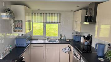 A modern kitchen with a window, a sink, a toaster, and a kettle.