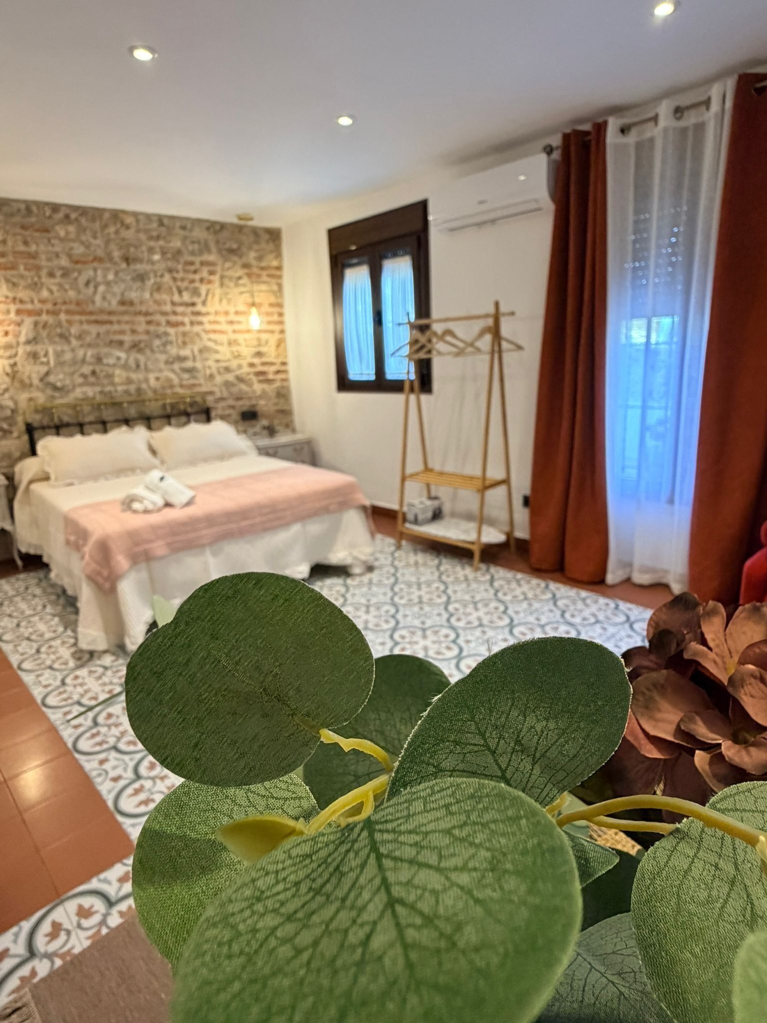 A hotel room with a bed, a wooden wall, a window with curtains, and a hanging laundry rack.