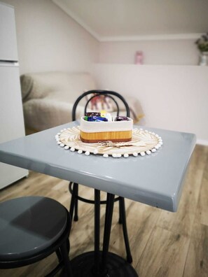 A small dining table with a cake on it, a chair, and a sofa in the background. - Feather House FH Wine Cellar (São Bartolomeu de Galegos)