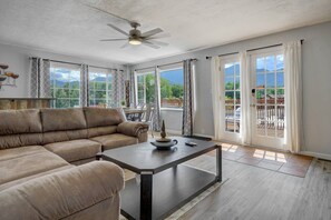 Un salon spacieux, comprenant un canapé, une table basse et un ventilateur de plafond.