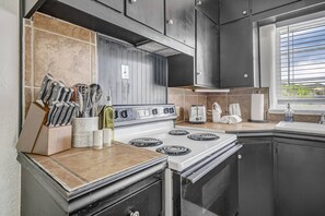 A kitchen with a stove, a toaster, and a window with blinds. - Pet-Friendly 2BR Penthouse with Mountain Views + Private Deck (Colorado Springs)