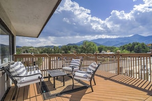 A wooden deck with outdoor furniture, a view of mountains, and a clear sky. - Pet-Friendly 2BR Penthouse with Mountain Views + Private Deck (Colorado Springs)