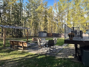 A backyard with a pergola, outdoor seating, a fire pit, and a wooden deck. - Casa de la Playa - Walk to the beach (Rimbey)