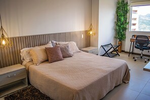 A modern bedroom with a large bed, bedside tables, a desk, and a chair. - Luxury 3BR Panoramic Views – El Tesoro Medellín (Medellín)