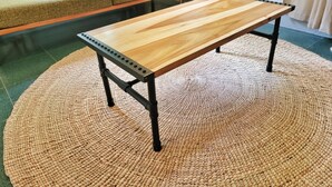 Ein Holztisch mit Metallbeinen auf einem gewebten Teppich.
