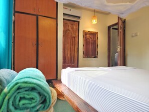 A bedroom with a bed, wooden wardrobe, and a wall-mounted cabinet. - Private 1BR Home | AC, Fast Wi-Fi & Full Kitchen (Dar es Salaam)
