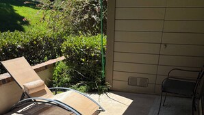 Un'area patio con pavimento in cemento, una sedia in metallo e una poltrona da relax.