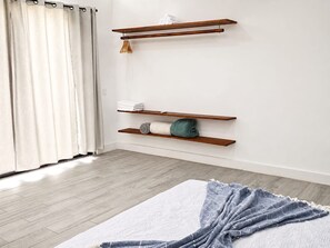 Ein Schlafzimmer mit einem Bett, Holzregalen und einem Fenster mit Vorhängen.