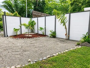 Ein Garten mit weißem Zaun, Kiesweg und unterschiedlichen Pflanzen.