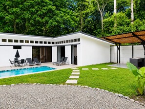 Une maison moderne dotée d’une piscine, d’un espace salon extérieur et d’un patio couvert.