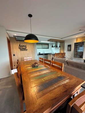 A modern dining area with a wooden table, chairs, and a pendant light.