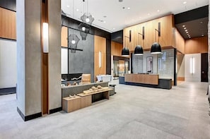Um lobby moderno com balcão de recepção, área de estar e luminárias contemporâneas.
