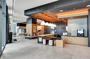 Um lobby moderno com balcão de recepção central, área de estar e estação de café.