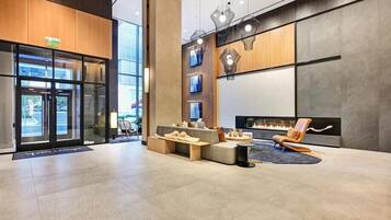Een moderne lobby met een open haard, zithoek en glazen entree.