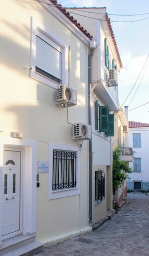 Edifici amb diverses unitats de climatització, una porta amb placa de número i una petita placa mural.