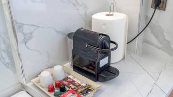 Eine Kaffeemaschine mit einer Kapselauflage und einer Rolle Küchenpapier auf einer Marmorarbeitsplatte.