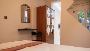 Quarto com cama, espelho, guarda-roupa de madeira e janela.