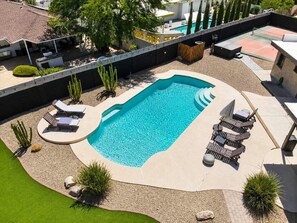 Ein Schwimmbecken mit Liegestühlen und einer überdachten Sitzgelegenheit.