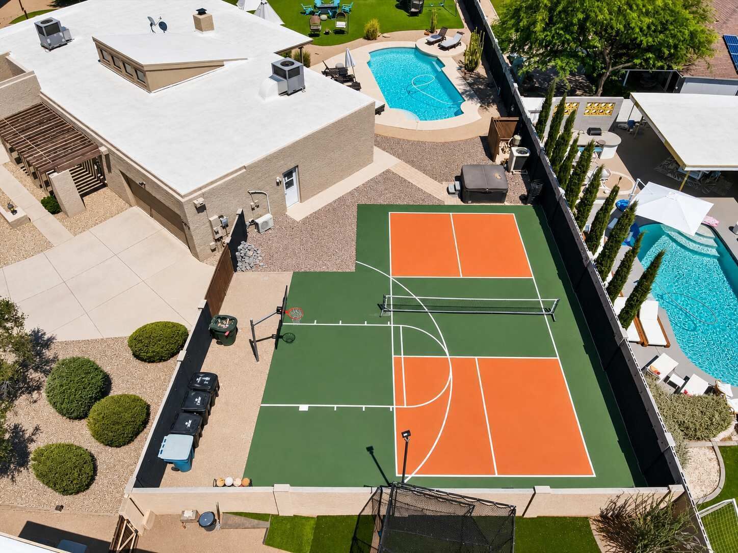 Vue aérienne d’une propriété dotée d’un court de tennis, d’une piscine et d’un espace salon abrité.