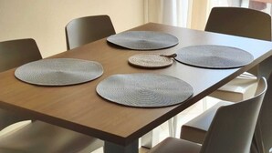 A dining area with a wooden table, four woven placemats, and a large mirror with a wooden frame. - HostySpot - Tropical Resort, 2-Bedroom Apartment (Santa Maria)
