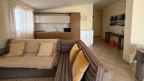 A modern living room with a sofa and a dining area. - HostySpot - Tropical Resort, 2-Bedroom Apartment (Santa Maria)