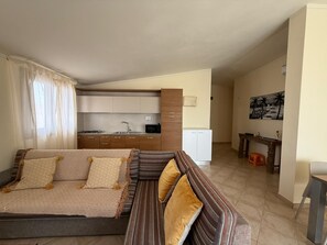 A modern living room with a sofa and a dining area. - HostySpot - Tropical Resort, 2-Bedroom Apartment (Santa Maria)