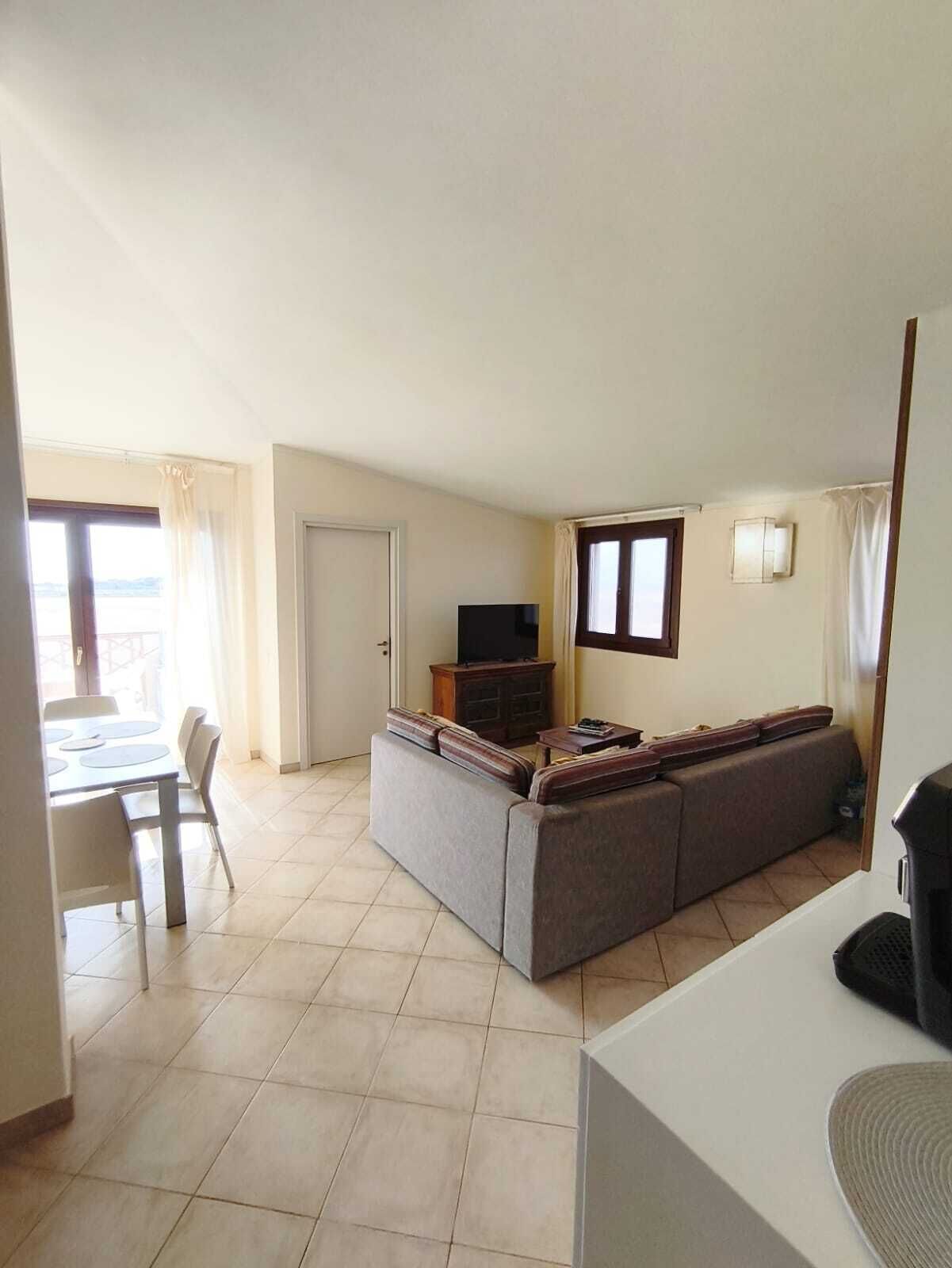 Un espacio de sala con un sofá, una televisión y una mesa de comedor con sillas.