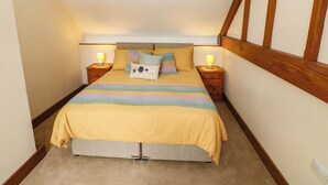A bedroom with a bed, two bedside tables with lamps, a wooden ceiling, and a carpeted floor. - Penrhiwoli Barn (Llangammarch Wells)