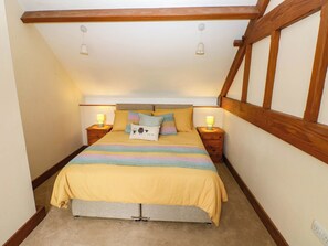 A bedroom with a bed, two bedside tables with lamps, a wooden ceiling, and a carpeted floor. - Penrhiwoli Barn (Llangammarch Wells)