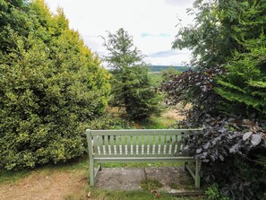 A bench in a park with dense foliage on both sides. - Penrhiwoli Barn (Llangammarch Wells)