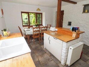 A kitchen with a wooden countertop, a white sink, and a stone wall. - Penrhiwoli Barn (Llangammarch Wells)