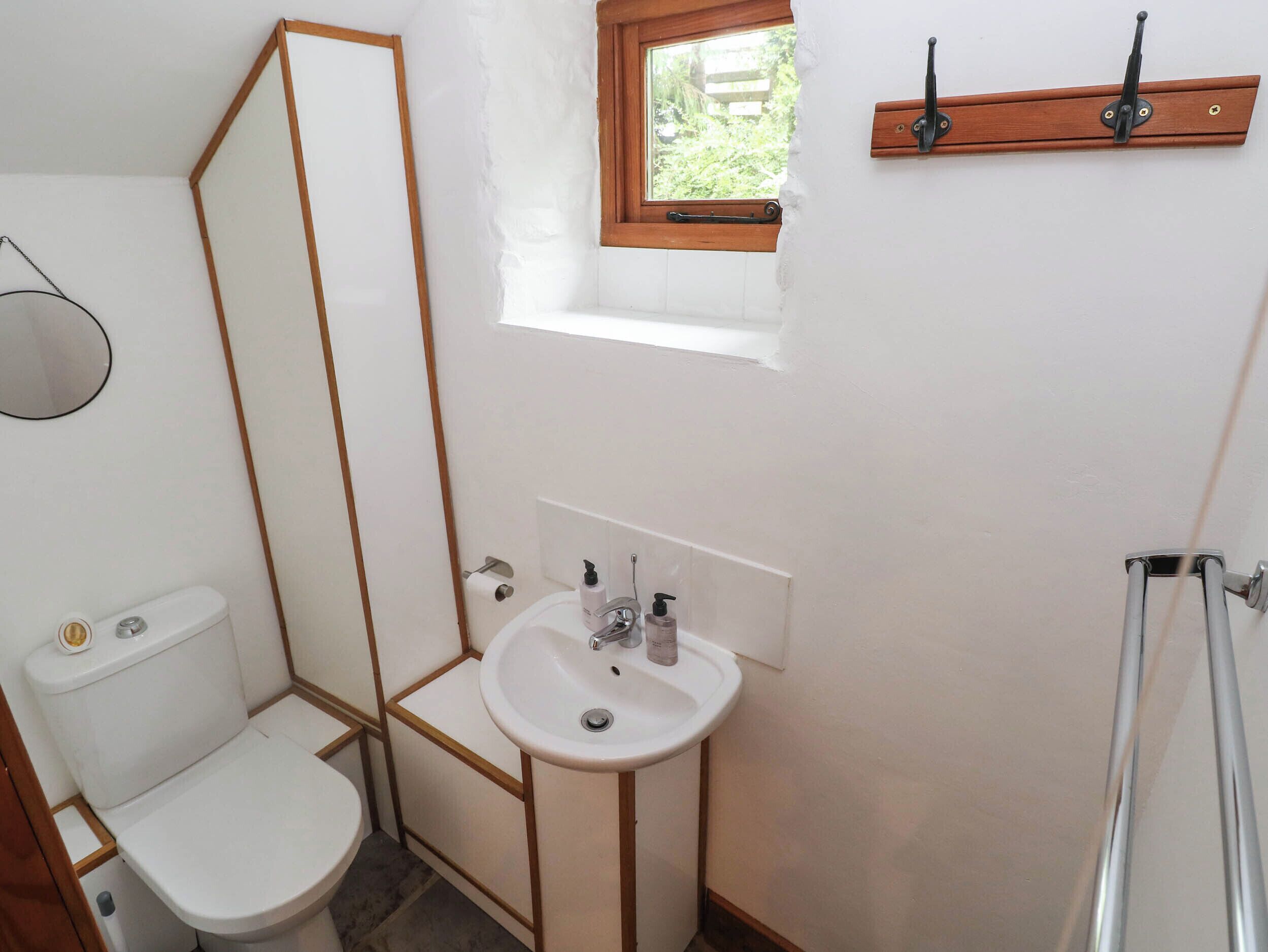 A bathroom with a toilet, sink, and a window.