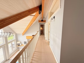 A hallway with wooden beams, a staircase, and a view of the outdoors. - Blue Baise - Tobermory Luxury Lakehouse (Tobermory)