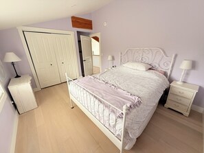 A bedroom with a bed, nightstands, a dresser, a door, and a mirror. - Blue Baise - Tobermory Luxury Lakehouse (Tobermory)
