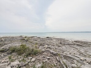 A rocky shoreline with a view of the sea and overcast sky. - Blue Baise - Tobermory Luxury Lakehouse (Tobermory)