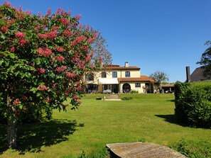 Una casa a due piani con un prato curato e un’area patio.