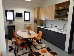 Una cucina moderna con tavolo da pranzo in legno, sedie e un piano di lavoro in marmo.