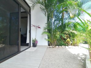 A modern building with a glass door entrance, a gravel pathway, and tropical plants. - Spacious apartment with fully equipped kitchen in beautiful Sámara (Sámara)